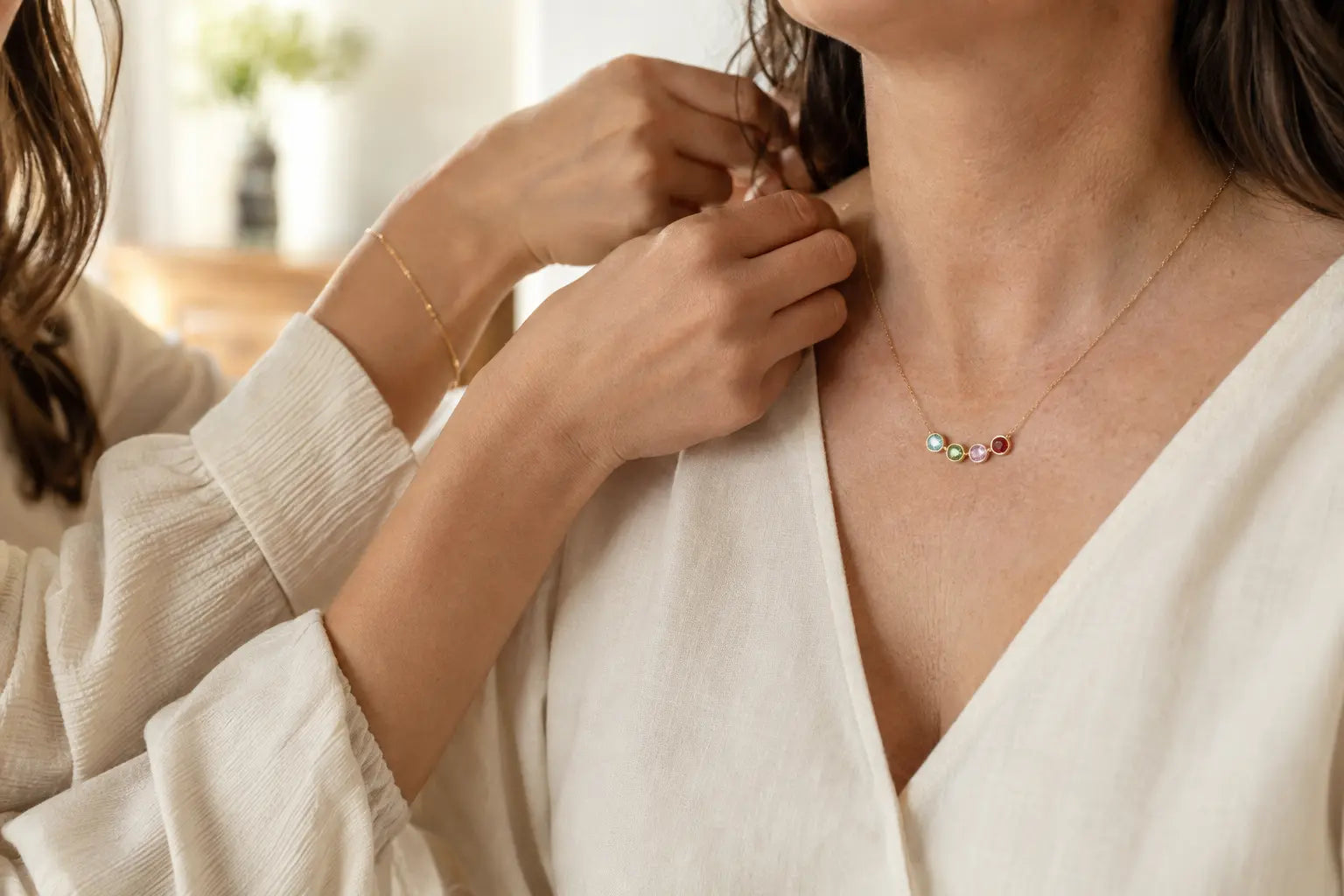 A family birthstone necklace being fastened with care